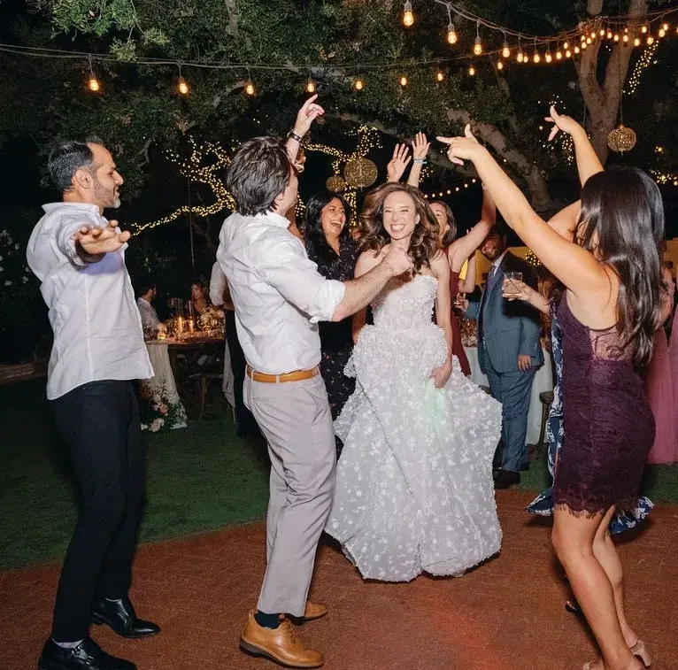 Bride dancing with guests under string lights at an outdoor Southern California wedding reception