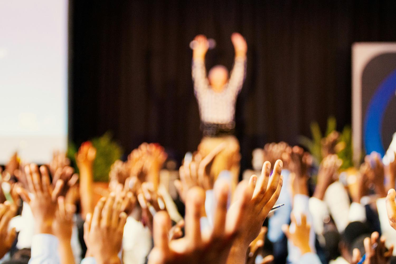 attendees at a conference cheer and raise hands
